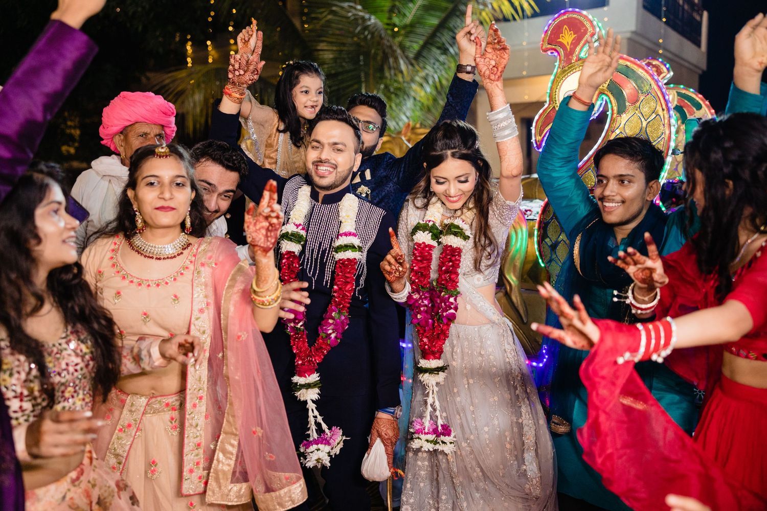 Joyful wedding celebration with guests dancing and enjoying festivities in traditional attire.