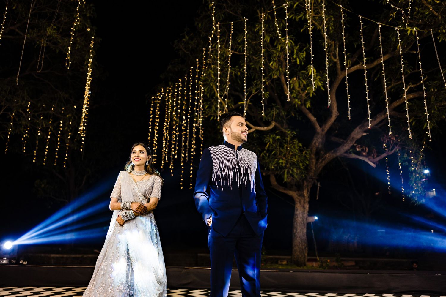 Stage performance featuring elegant costumes and dramatic lighting with hanging string lights in background.