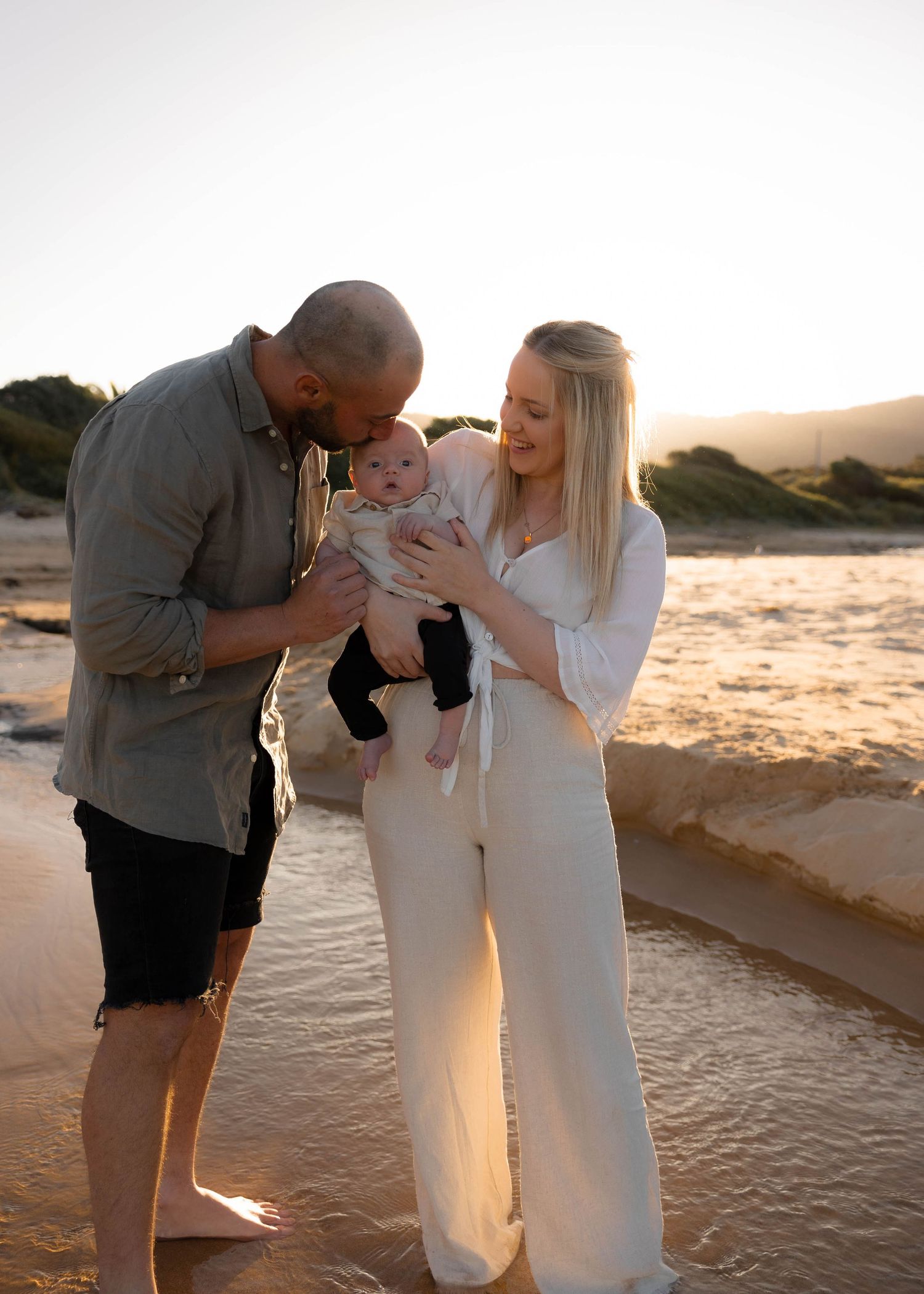 Mum, dad and their newborn baby sharing a peaceful moment at Woonona beach. Timeless family outdoor and in home photoshoot in the Illawarra.