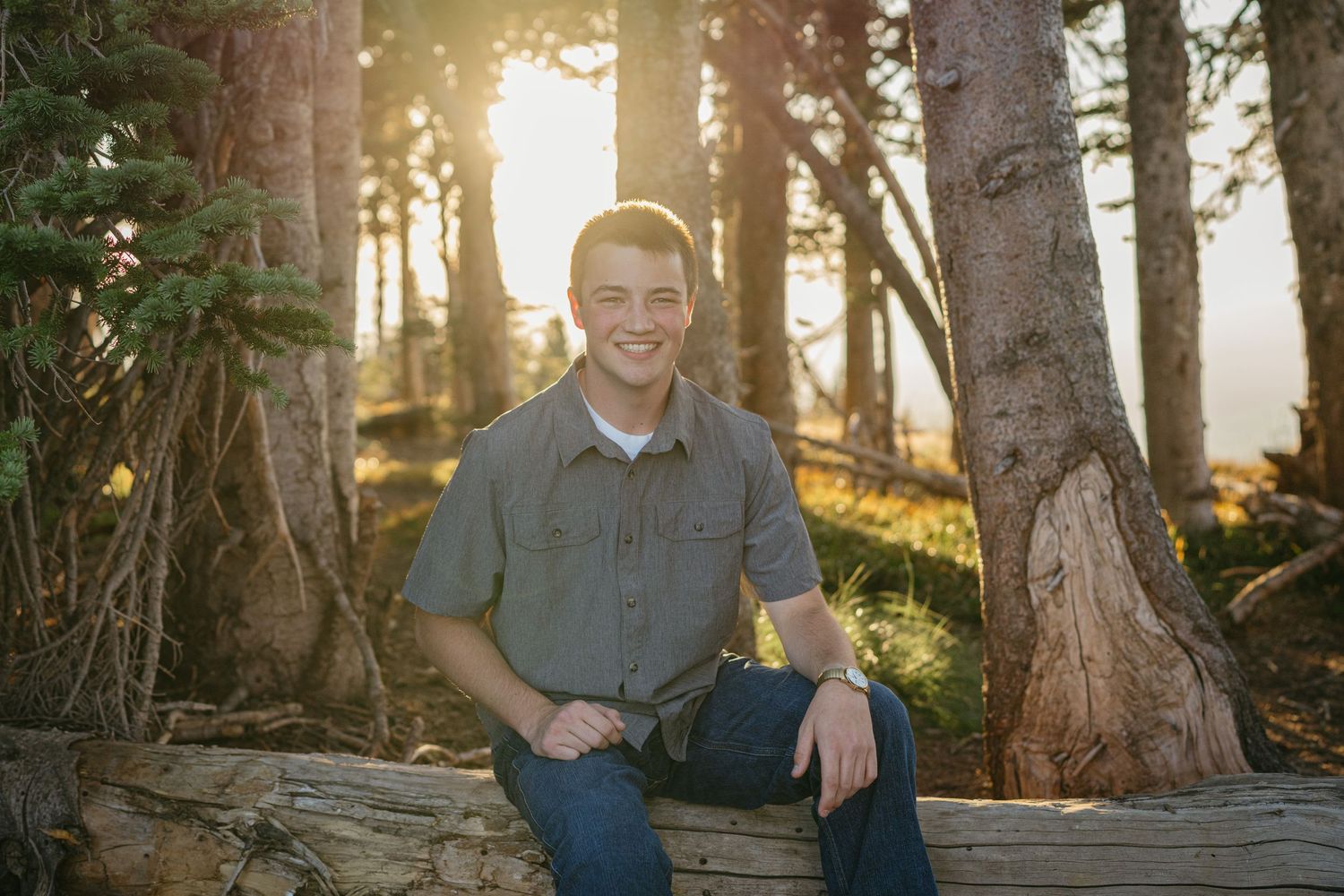 Warm sunset portrait in forest with glowing golden light filtering through pine trees.