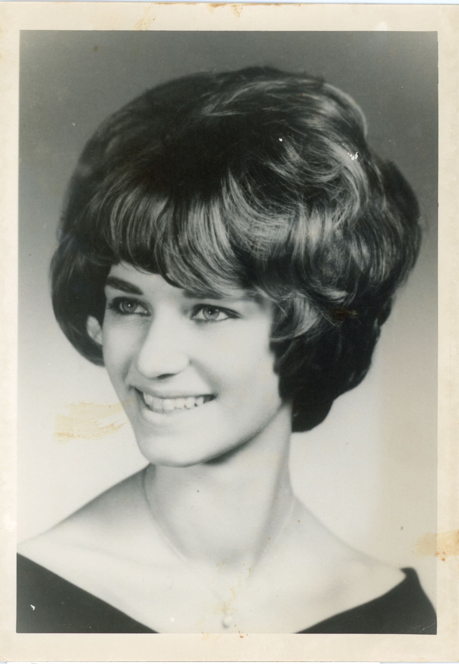 A vintage black and white portrait photograph featuring a 1960s bouffant hairstyle.