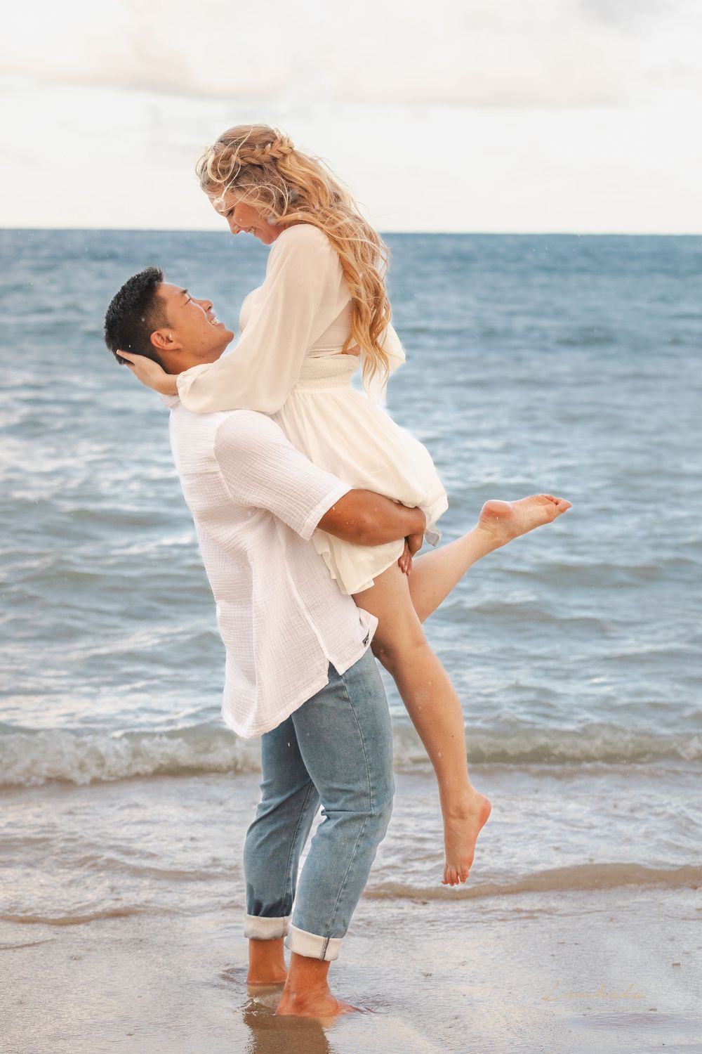 A playful couple shares a joyful moment at the ocean's edge.