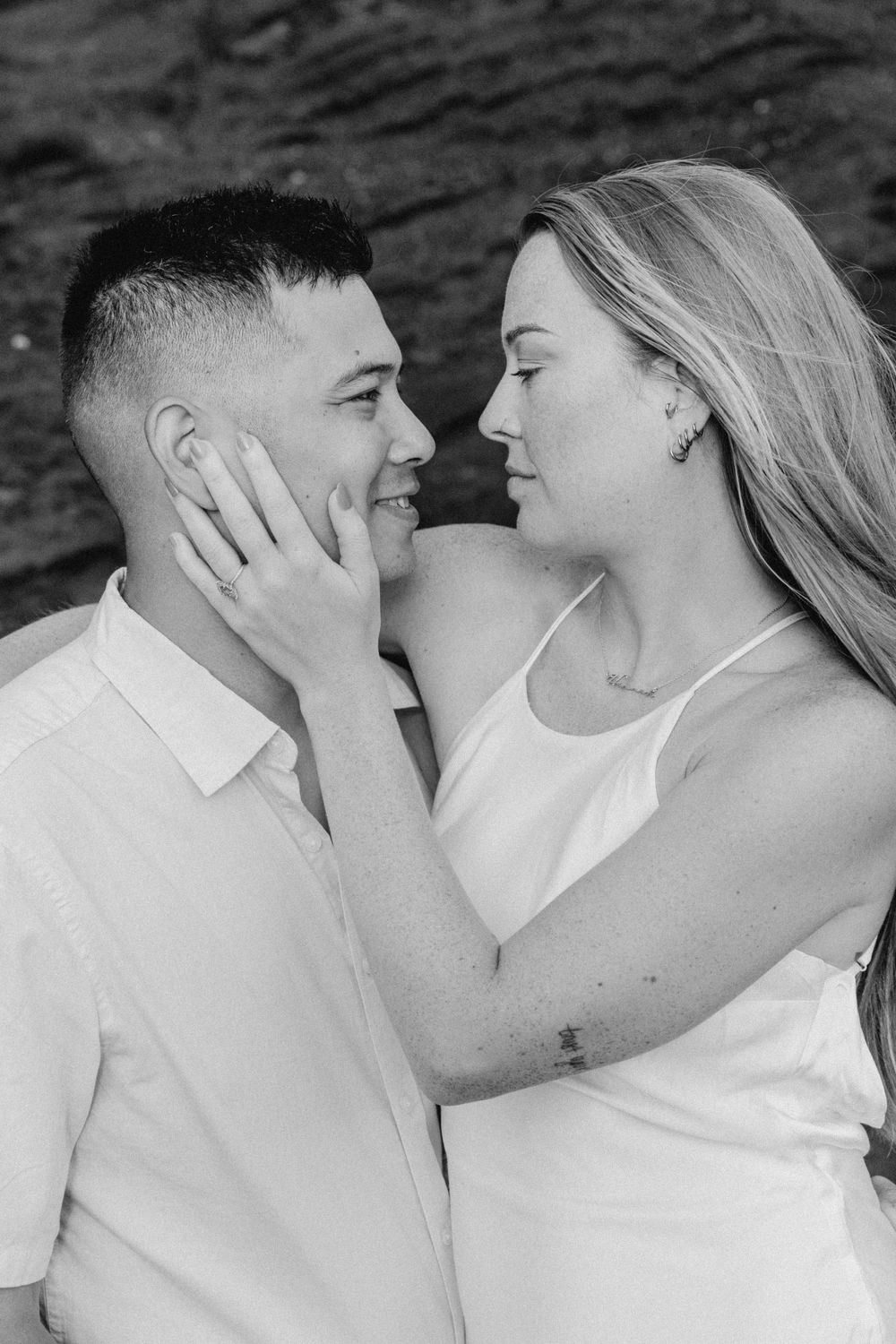 Black and white portrait of couple in white clothing sharing an intimate moment.