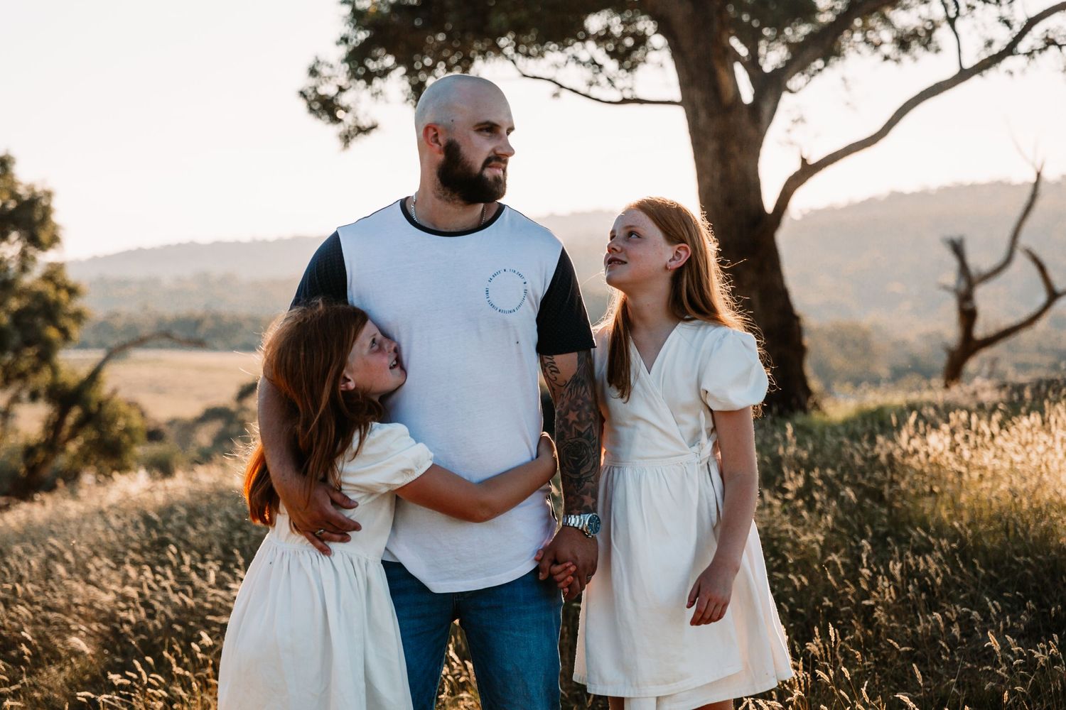 Fatherhood, a father with his daughters, standing in the bush at sunset