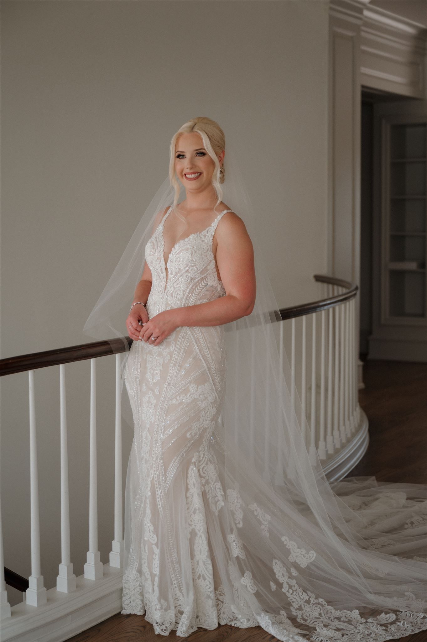 Beautiful lace wedding dress with plunging neckline and cathedral veil photographed on elegant staircase.
