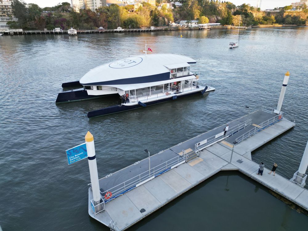 Double-decker passenger ferry docked at floating pontoon on river.