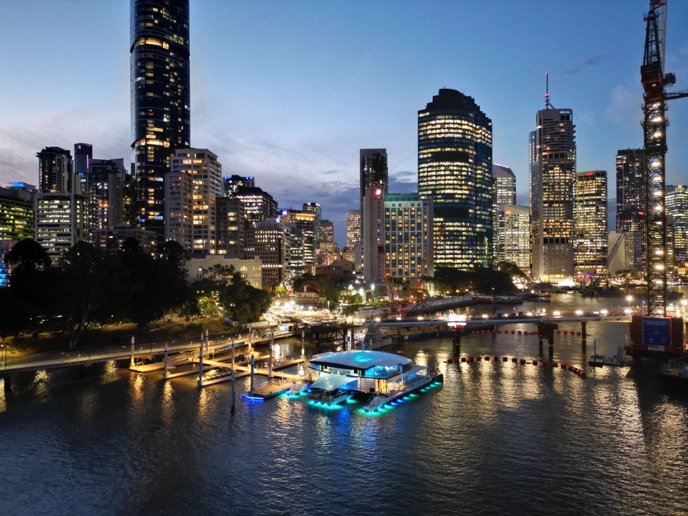 Stunning night view of Brisbane River featuring an illuminated floating platform against city backdrop.