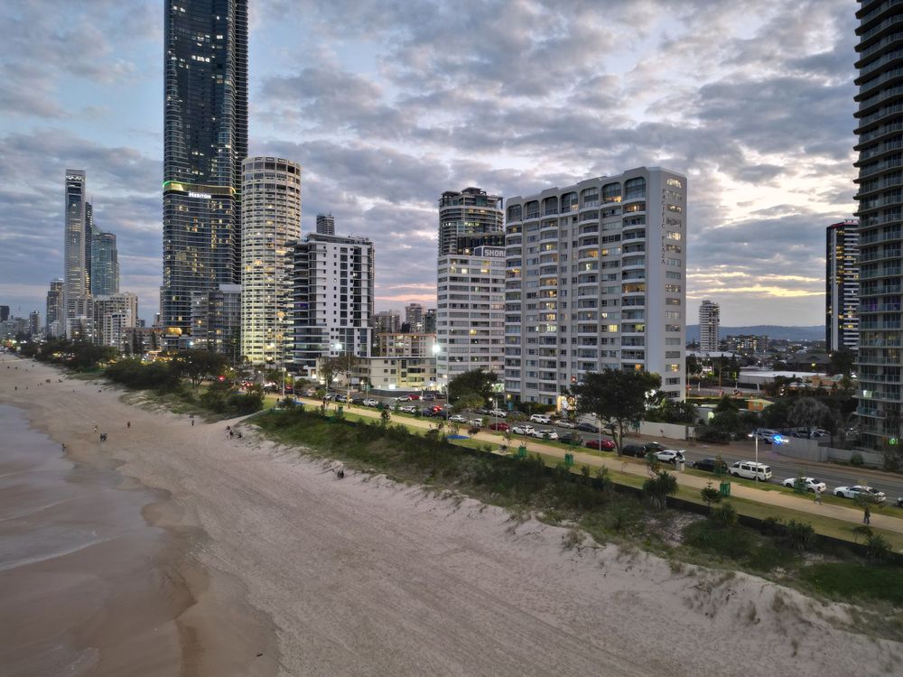 High-rise buildings line Surfers Paradise beach at dusk with dramatic cloudy sky.