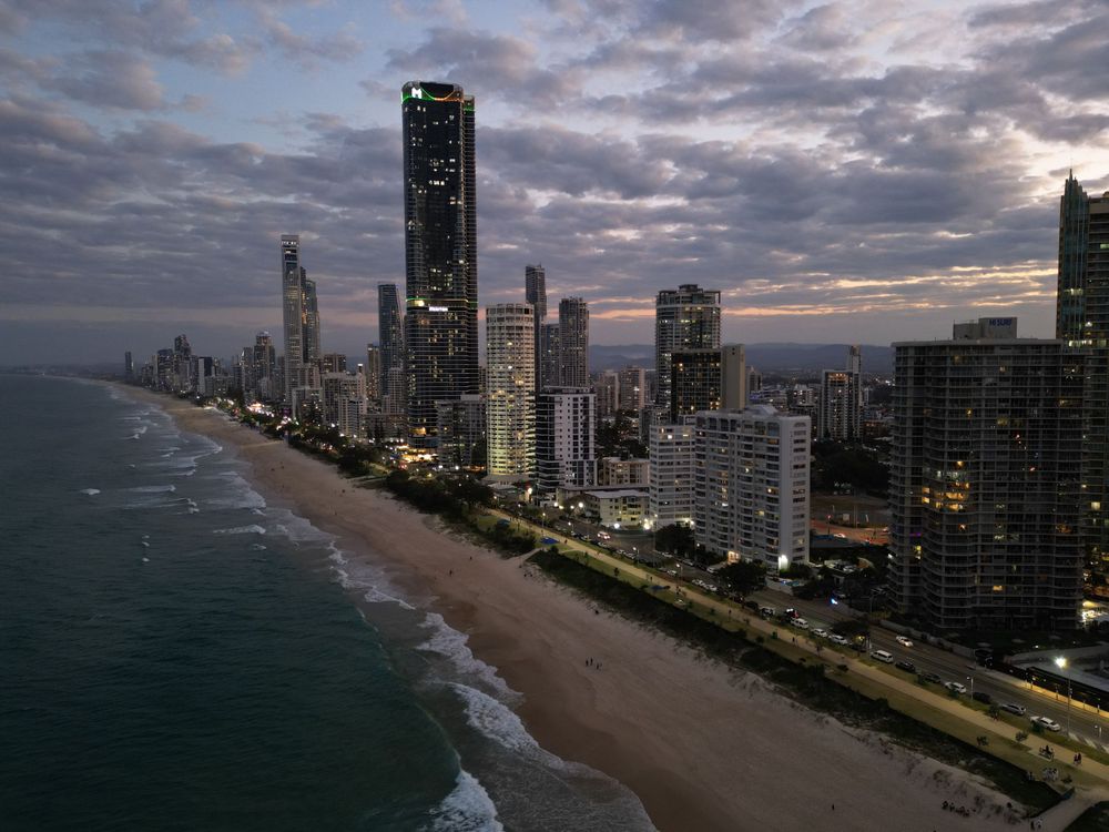 Dusk settles over Surfers Paradise beachfront with waves crashing along shoreline.