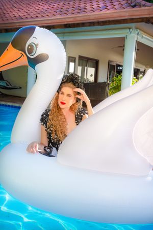 Summer pool photo with large inflatable swan float in bright sunlight.
