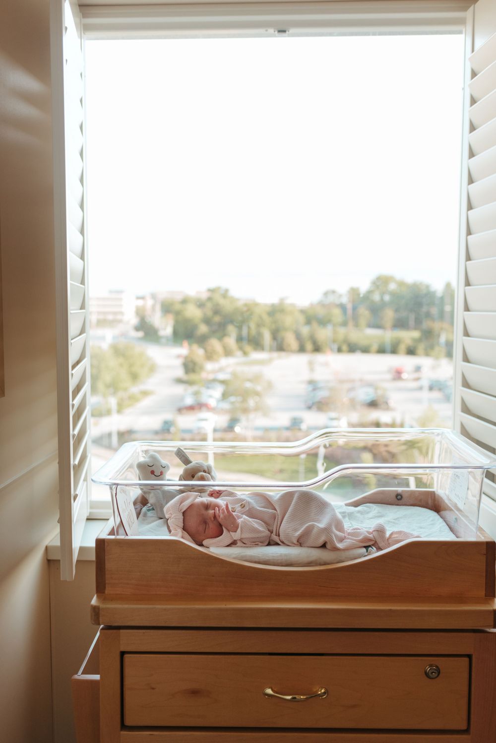 A peaceful nursery corner with white shutters and wooden furniture bathed in natural light.