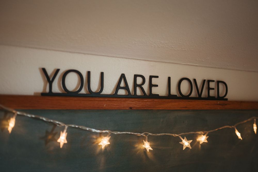 Decorative wall text reading 'YOU ARE LOVED' with twinkling string lights below.