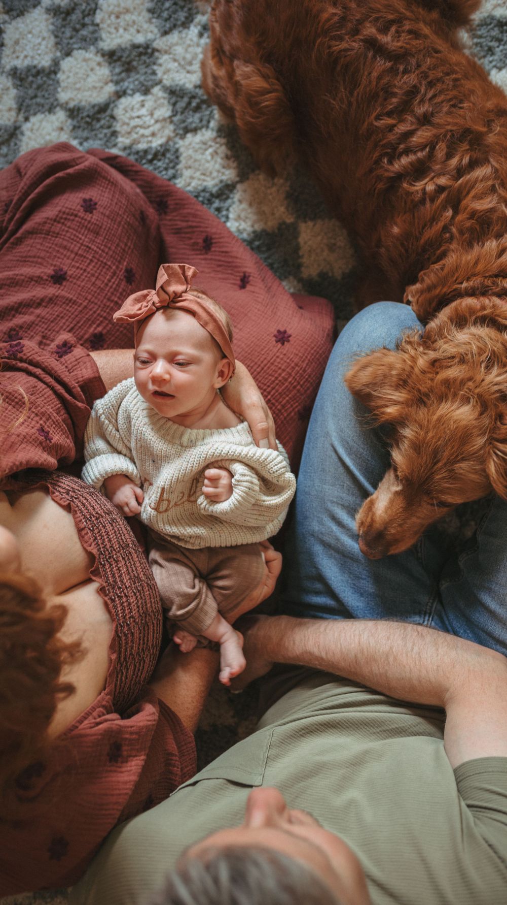 Relaxed family moment on a patterned rug with a golden retriever.