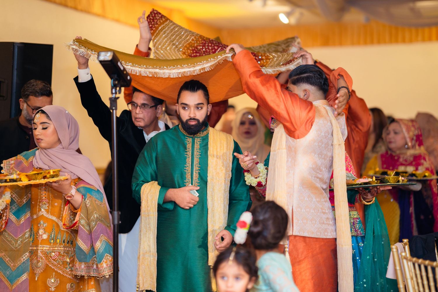 A festive celebration with people lifting colorful decorative items during a cultural ceremony.