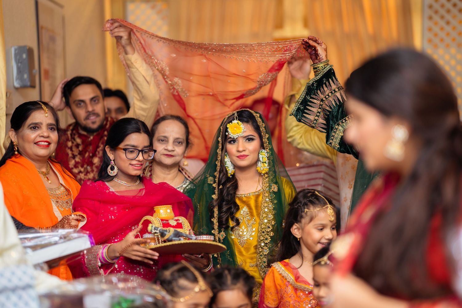 Traditional South Asian mehndi ceremony with guests gathered around celebrating with colorful scarves.