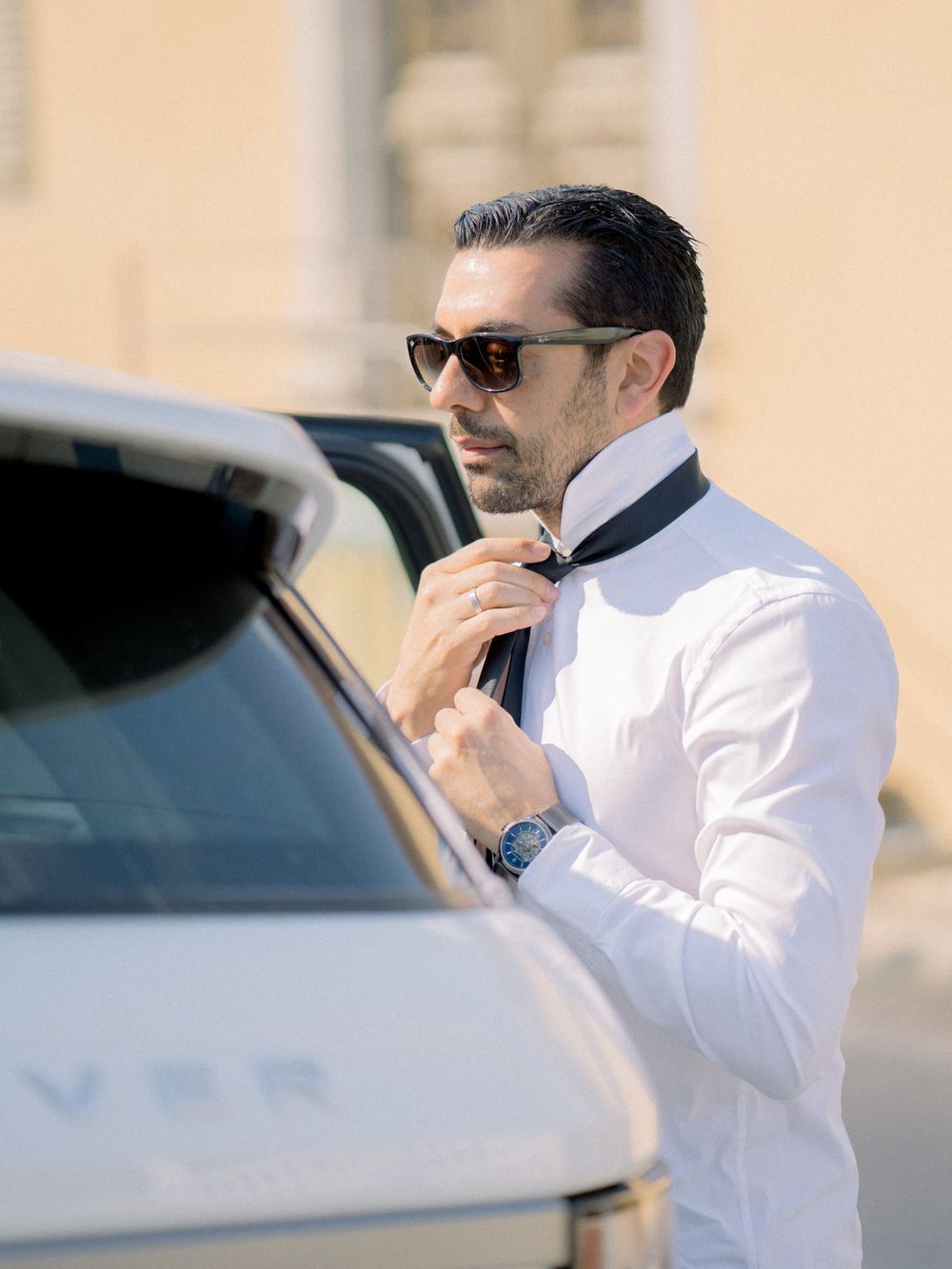 Destination wedding in Cyprus, Lefkara village Groom fixing tie in front of car