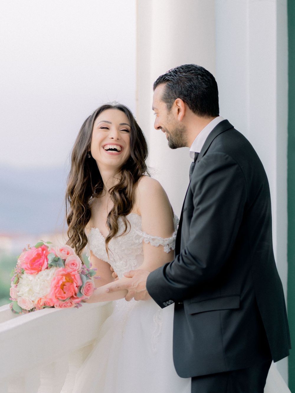 Bride and Groom having fun, hugging at a balcony with a panoramic view in Cyprus
