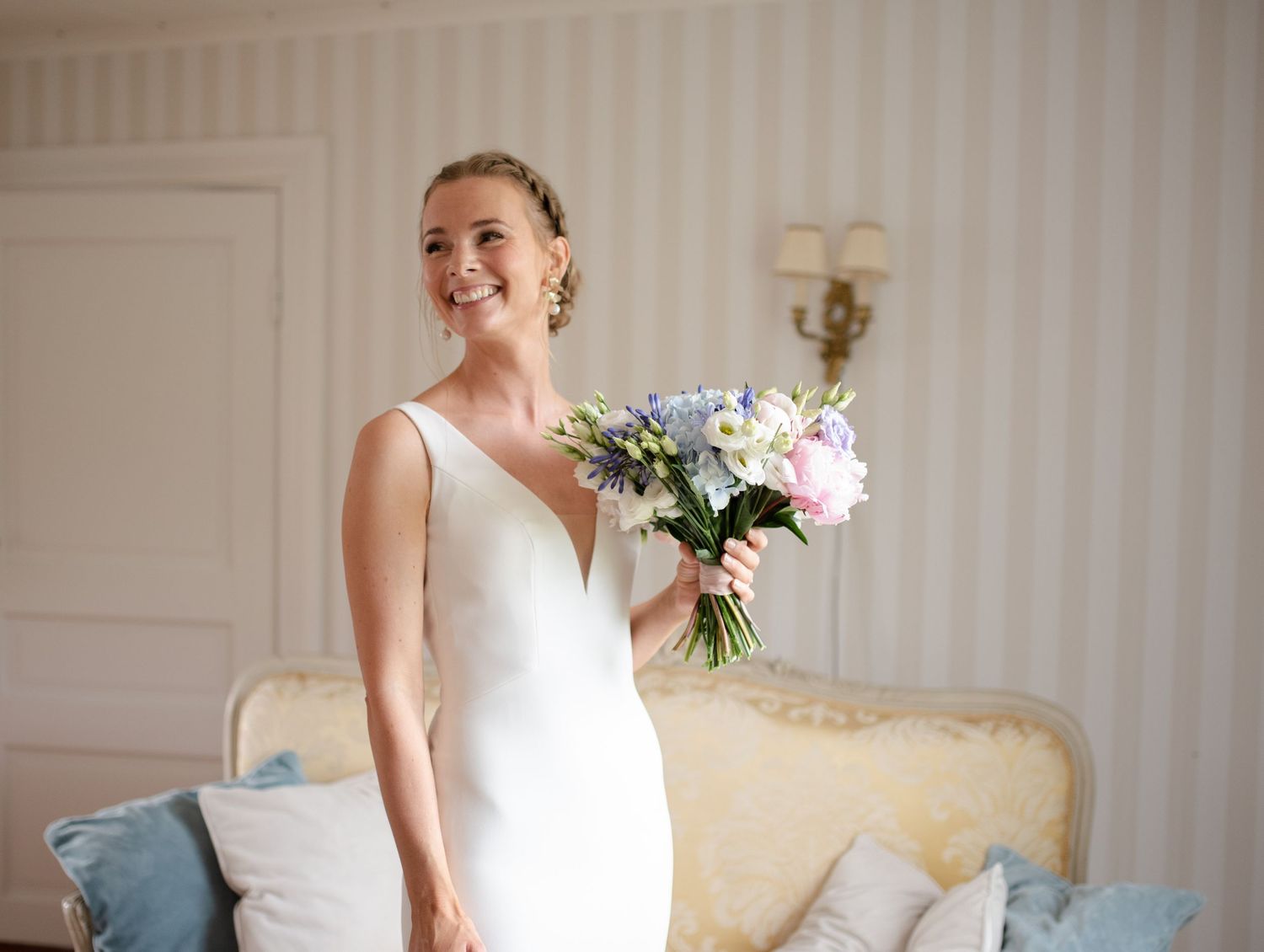 A person in a white wedding dress holds a bouquet of pink and white flowers.