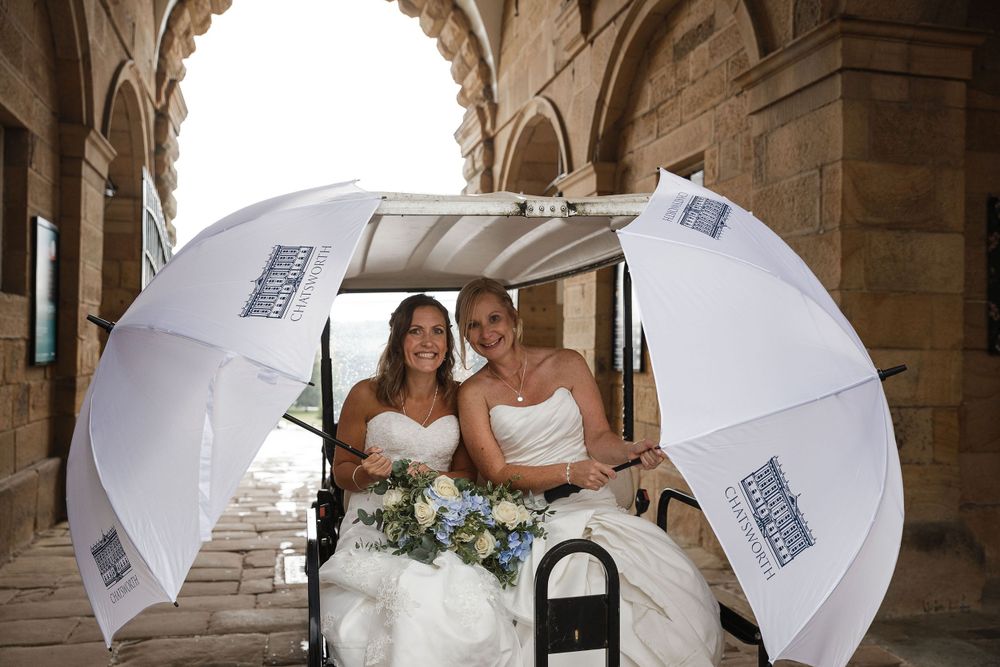 White parasols create elegant framing in stone archway wedding photos.
