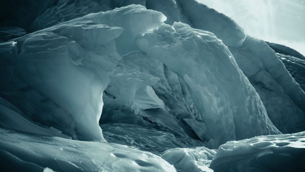 Ethereal blue ice cave formations with smooth curved surfaces.