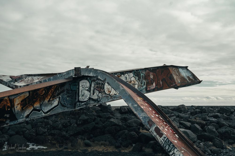 Rustic abandoned bridge structure with graffiti against cloudy sky.