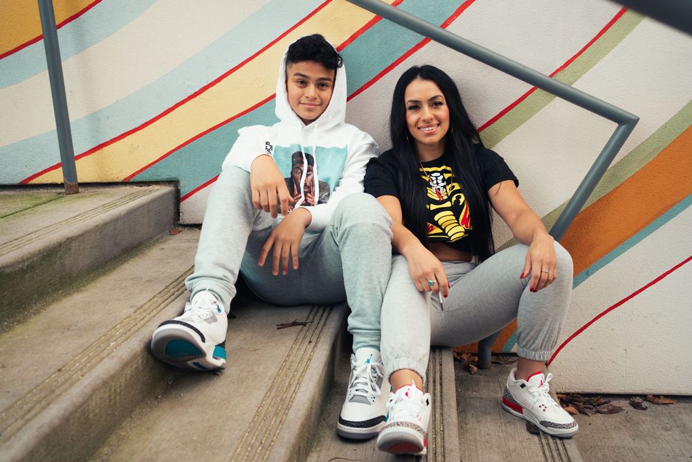 Friends sitting on steps against colorful mural wall wearing casual urban attire.
