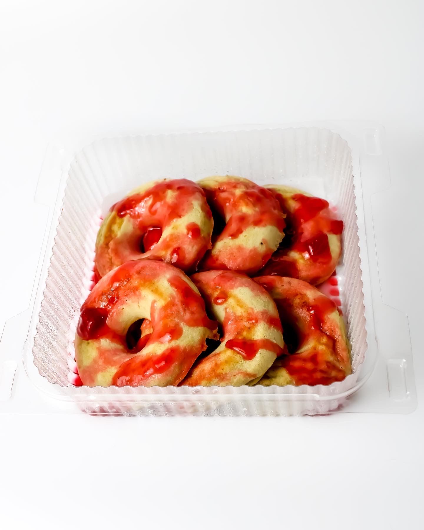 Red-sauced dumplings arranged in a white plastic takeout container.