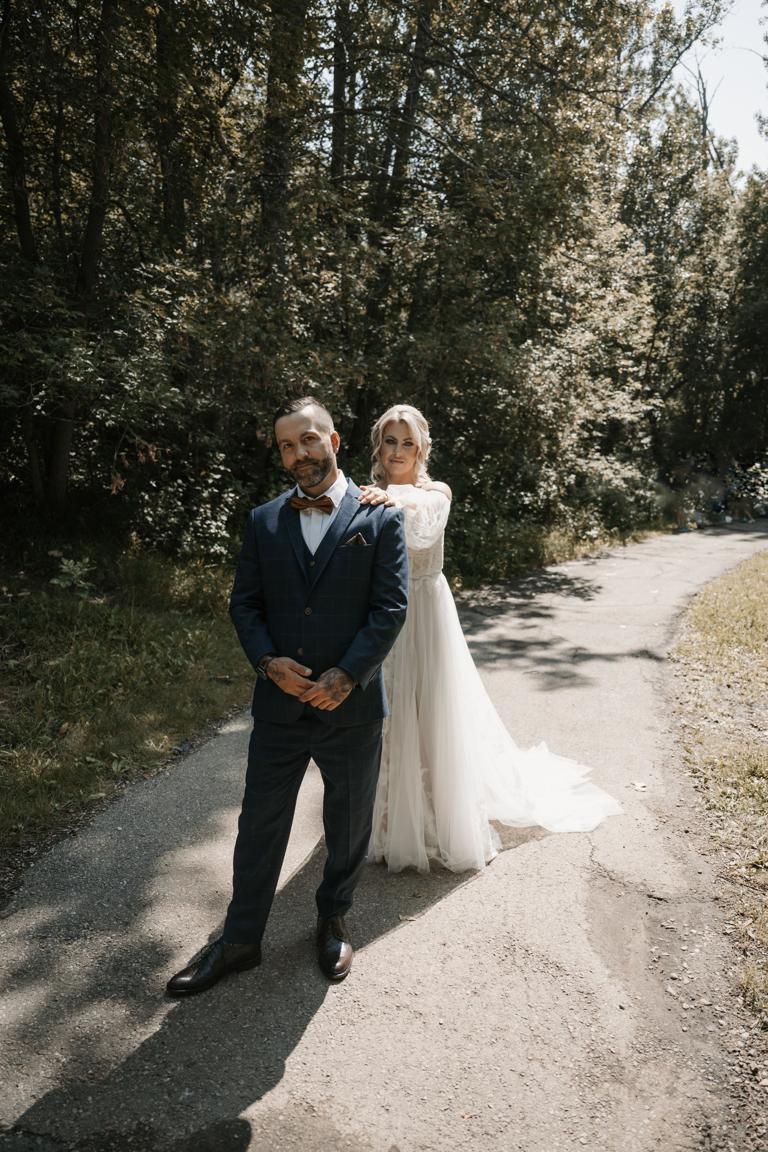 A couple shares a quiet first look moment on a sunlit forest path before their wedding ceremony.