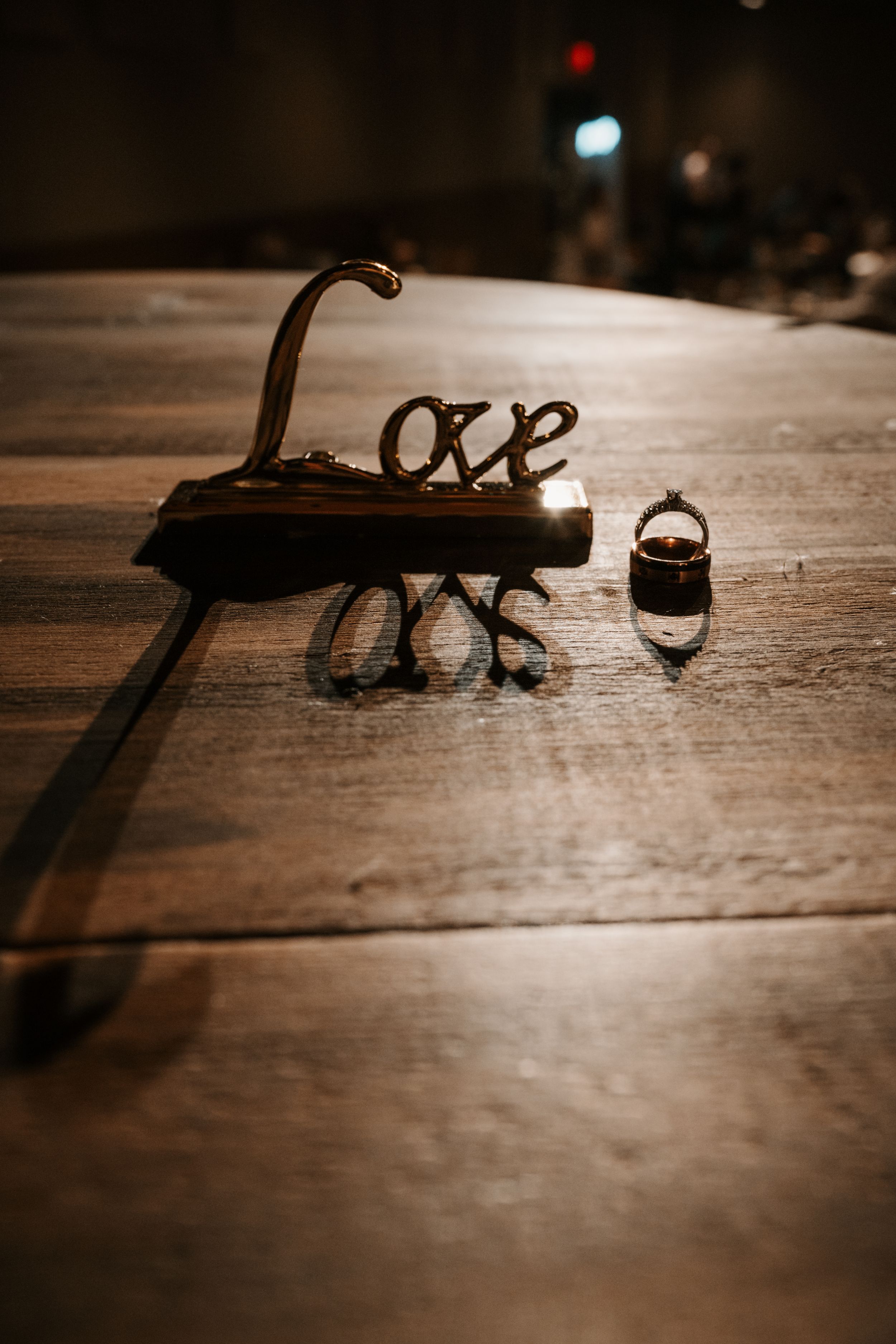 A dark wooden surface displays cursive 'love' shadows cast from a decorative metal piece with dim lighting in the background.