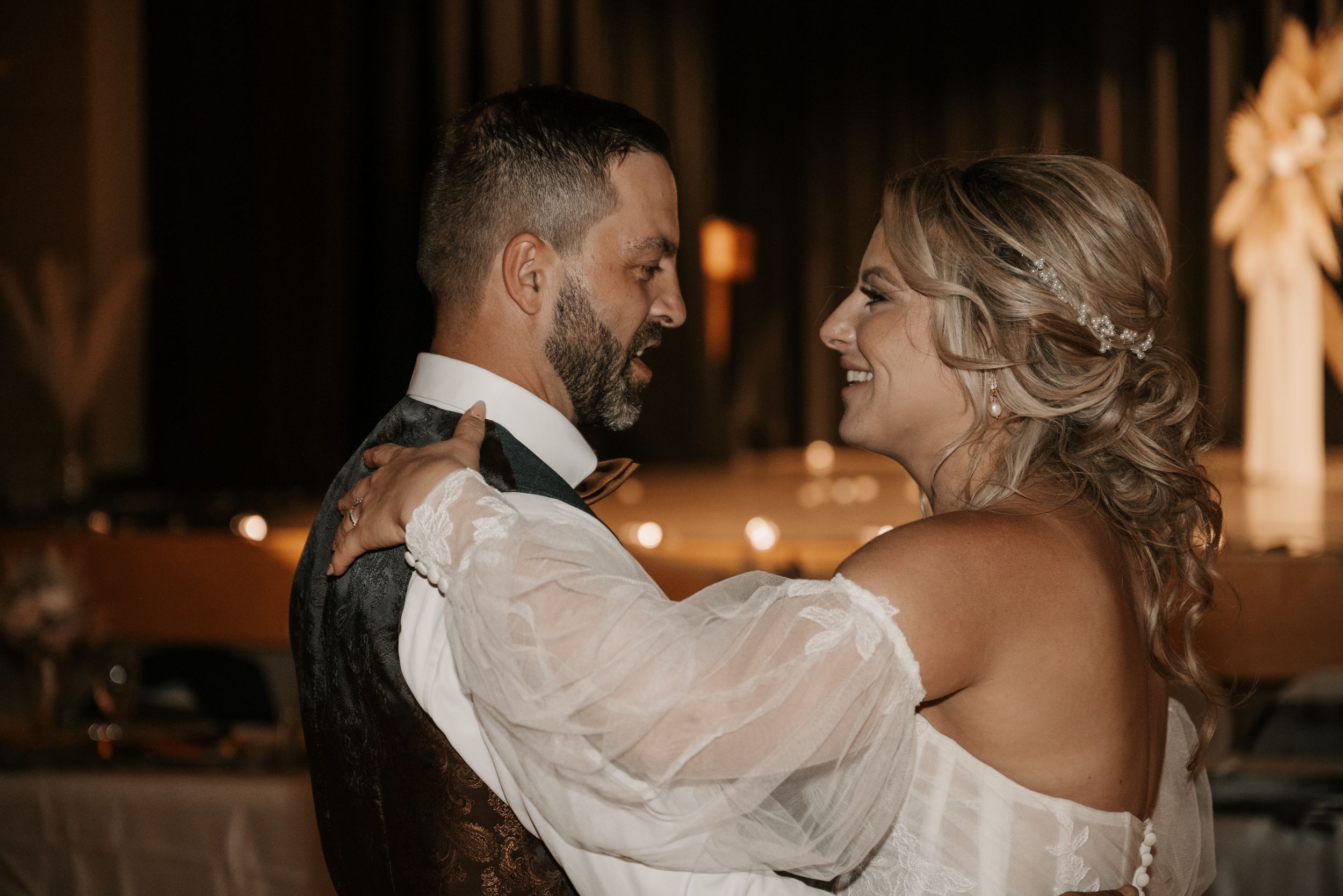 Happy couple shares an intimate dance moment together at their wedding reception in romantic candlelit setting.