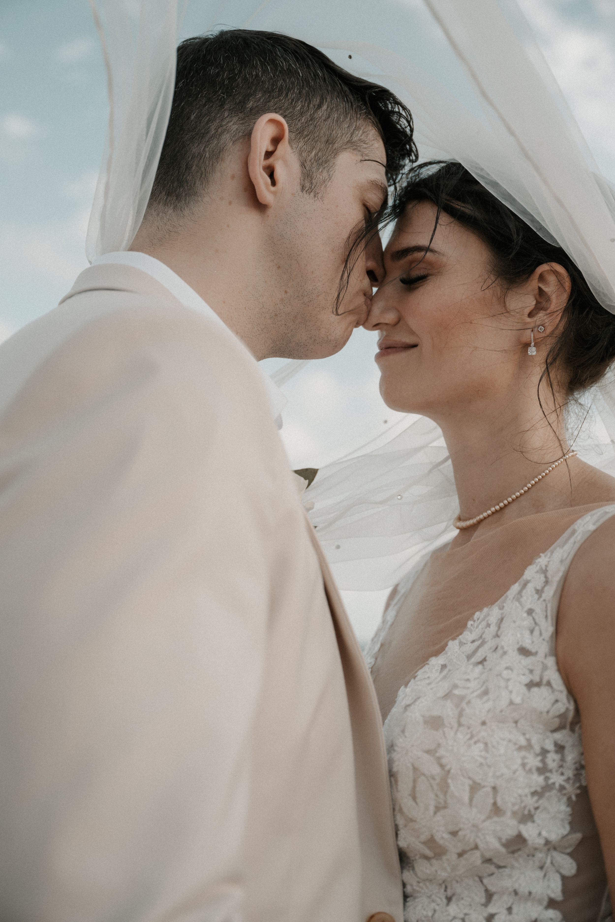 A close-up wedding portrait showing a tender moment between newlyweds under soft lighting.