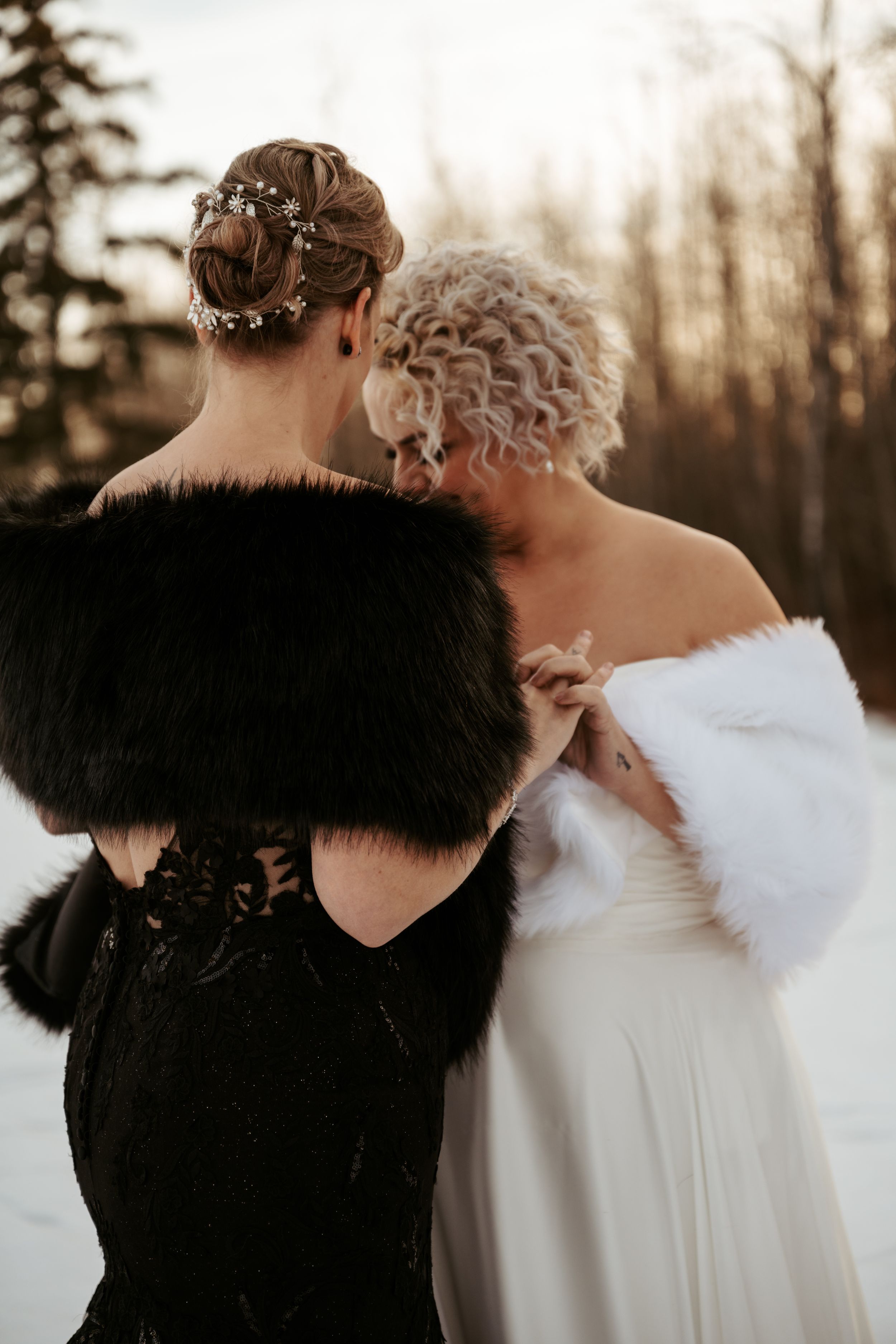 A couple share an intimate moment while wearing elegant black and white fur stoles during a winter celebration.