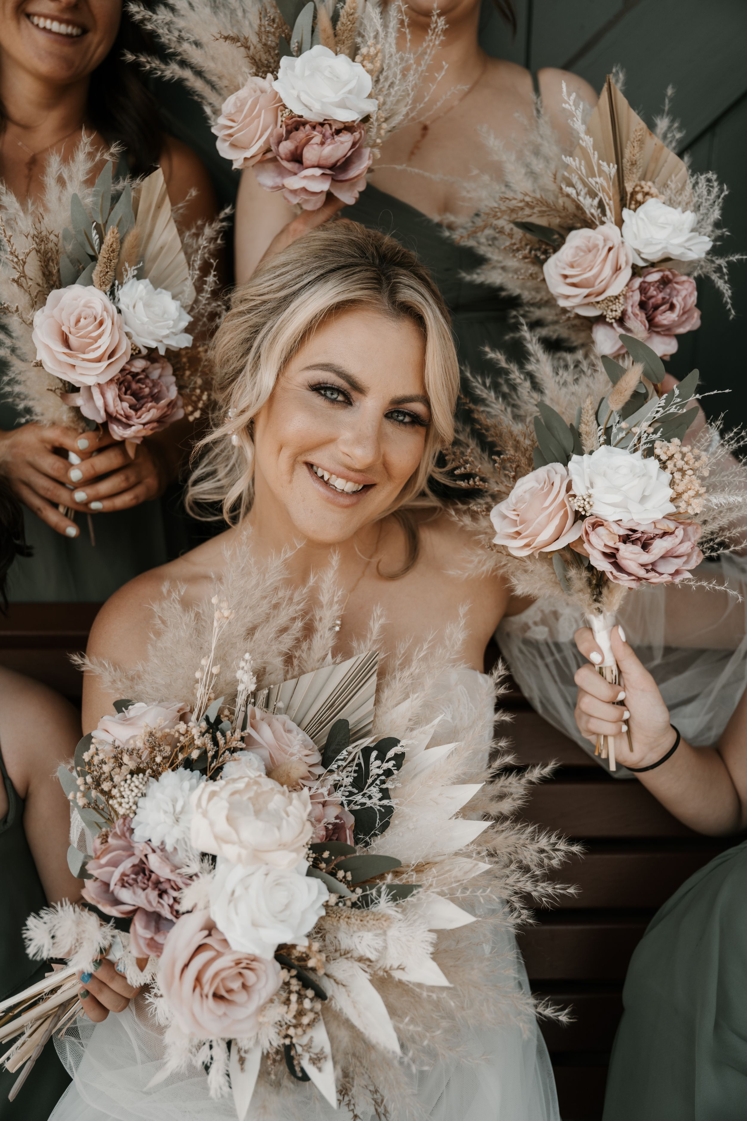 Beautiful wedding bouquets featuring blush roses, dried pampas grass and white florals in a rustic bohemian style.