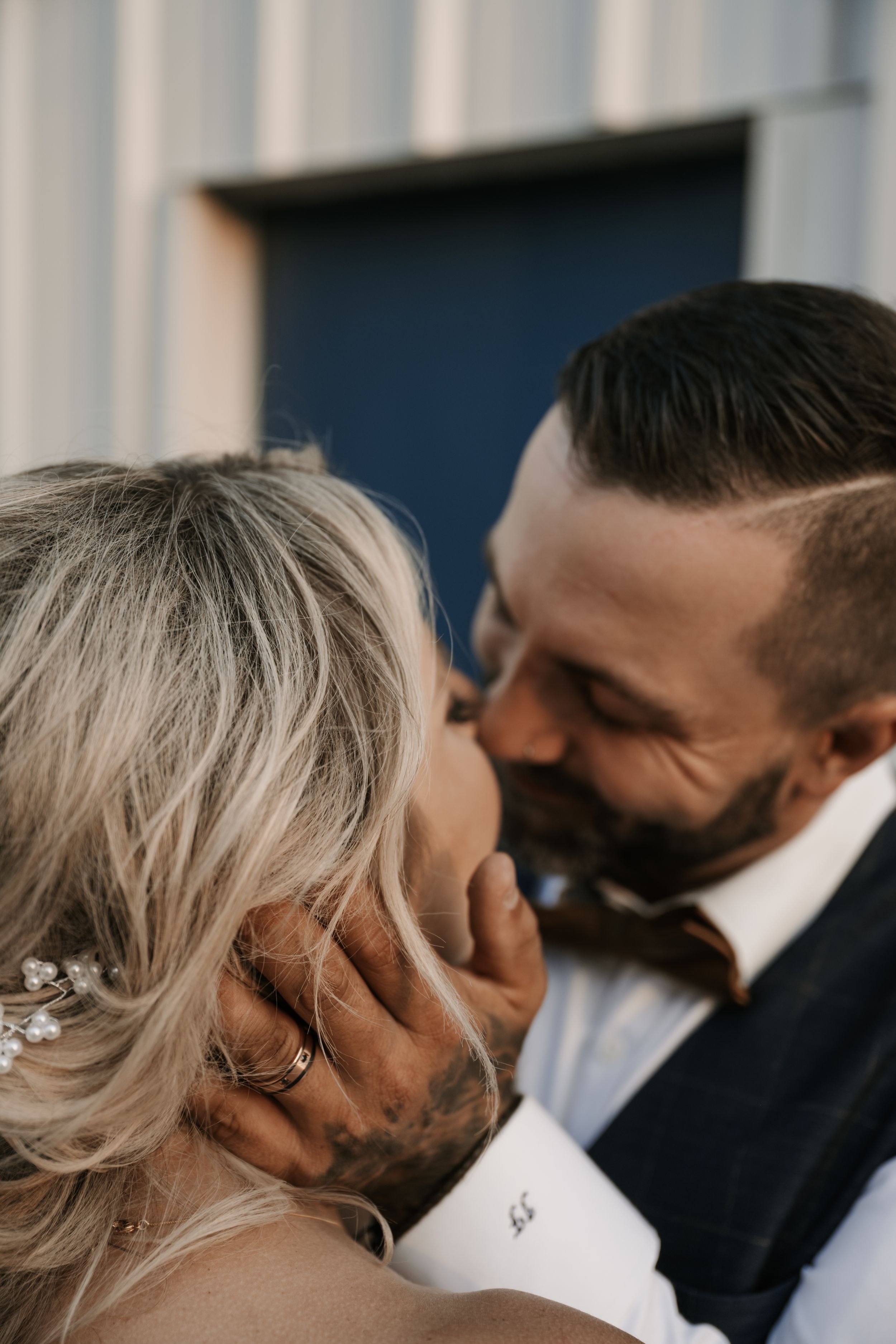 A romantic close-up of a couple sharing an intimate moment during their wedding, with blonde hair against dark attire.