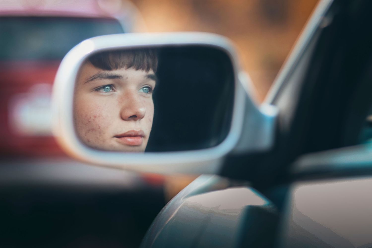 Reflection in car side mirror showing contemplative gaze through glass.