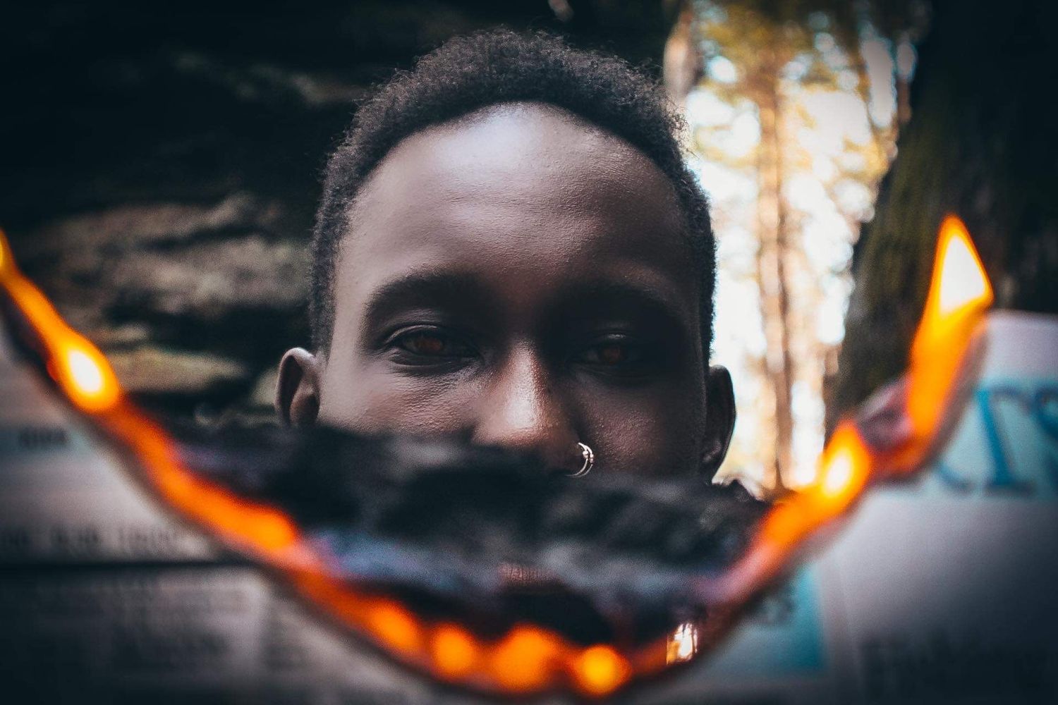 Creative portrait through orange flame effect with dark moody lighting.