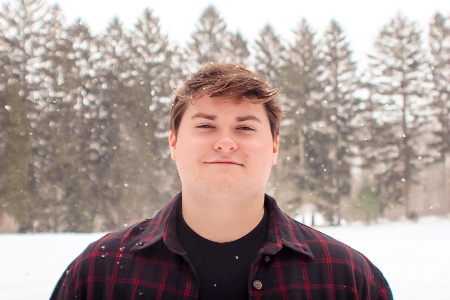 Winter portrait in snowy forest with person wearing plaid flannel shirt.