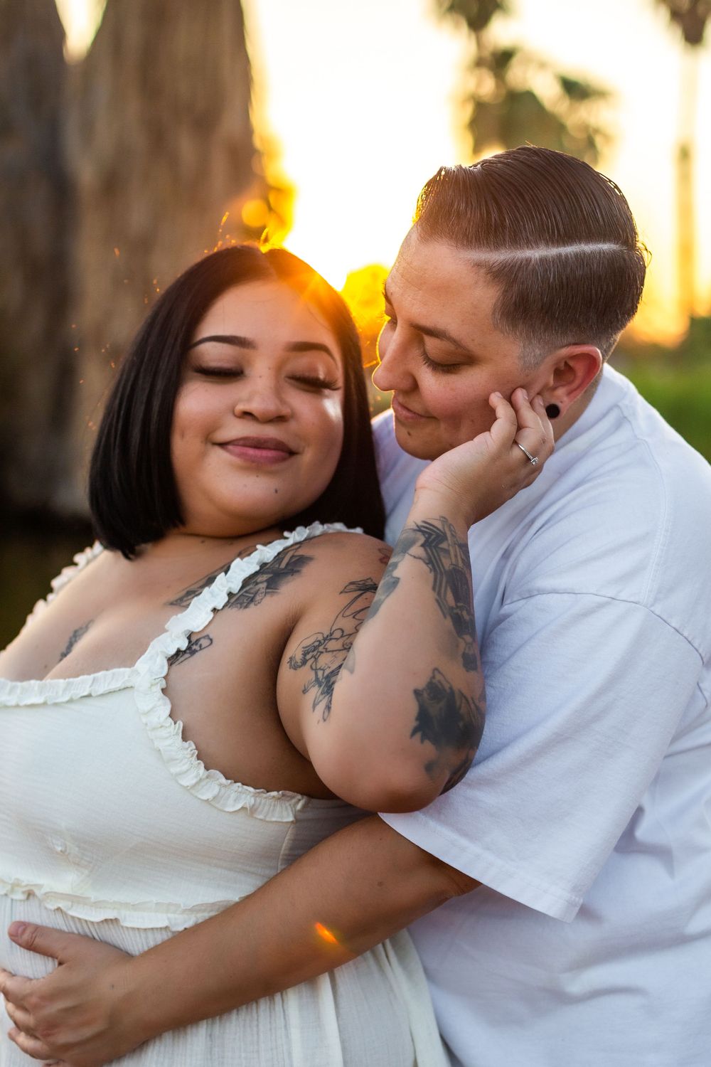 Intimate couple portrait with sunset backlighting in white summer outfits.