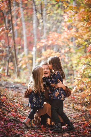 A joyful embrace captured in a forest setting with warm fall colors.
