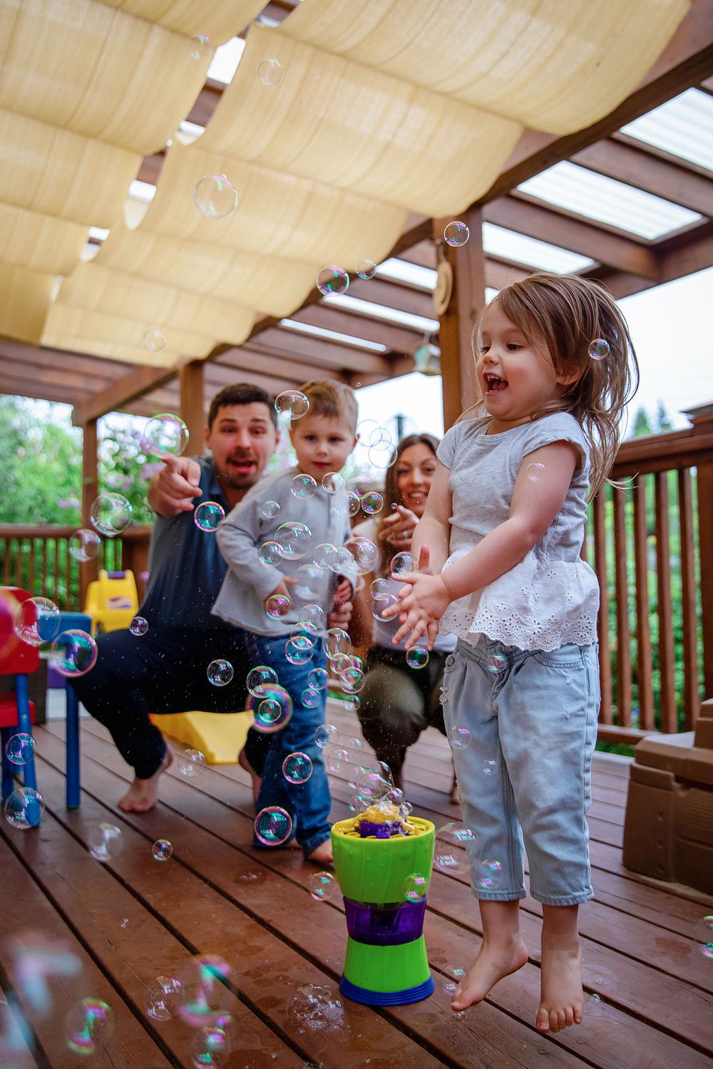 Children playing with bubbles on wooden deck during outdoor playtime.