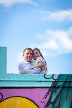 Cheerful moment shared on a colorful graffiti wall against blue sky.