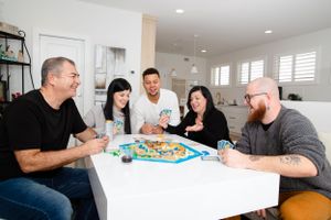 Friends gathered around a white table playing a board game together.