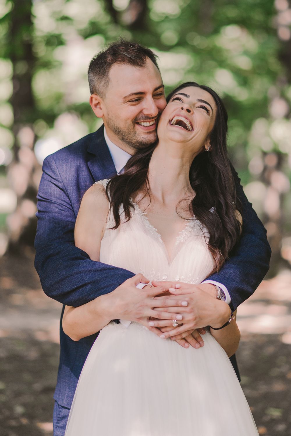 Couple shares candid laughing moments during their wedding photoshoot in a park.