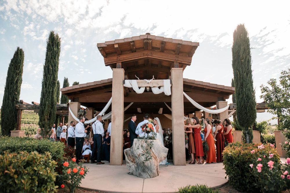 Outdoor wedding venue with Mediterranean style architecture and cypress trees.
