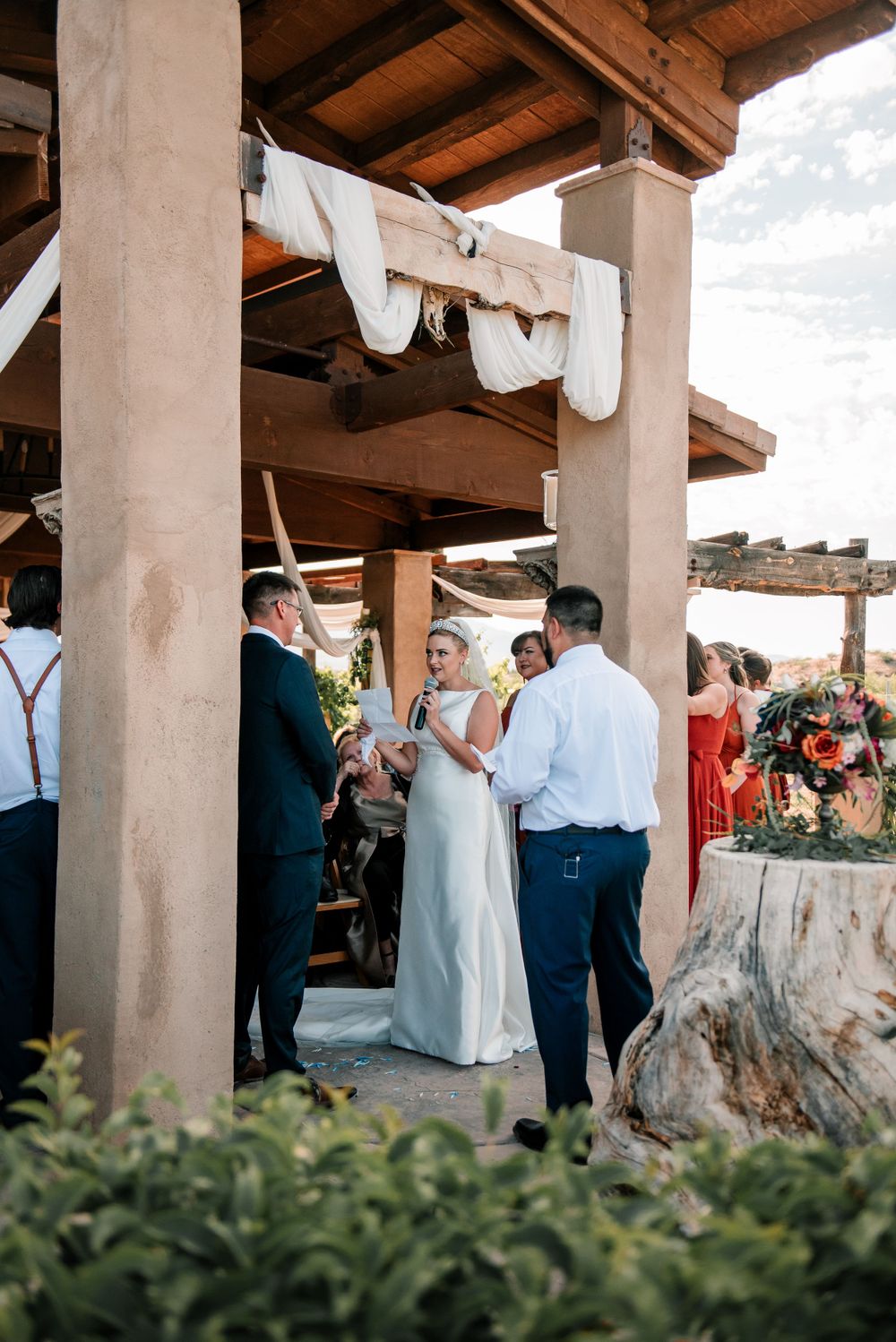 Reception gathering under a covered patio with wooden beams and pillars.