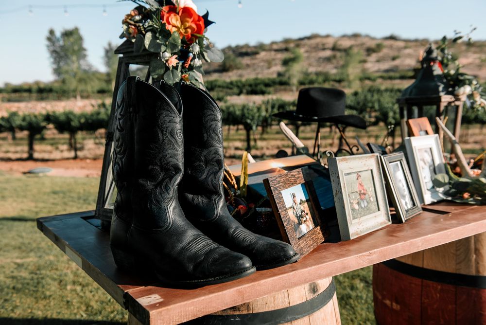 Black boots and picture frames arranged on wooden barrels at an outdoor venue.