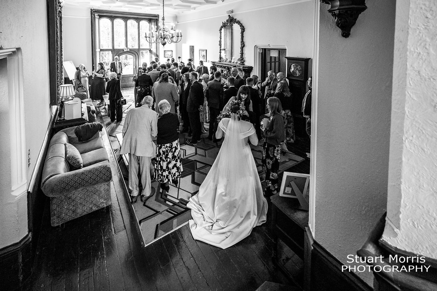wide shot of wedding guests after the ceremony in one of the rooms at Ruthin castle north Wales wedding photographer.