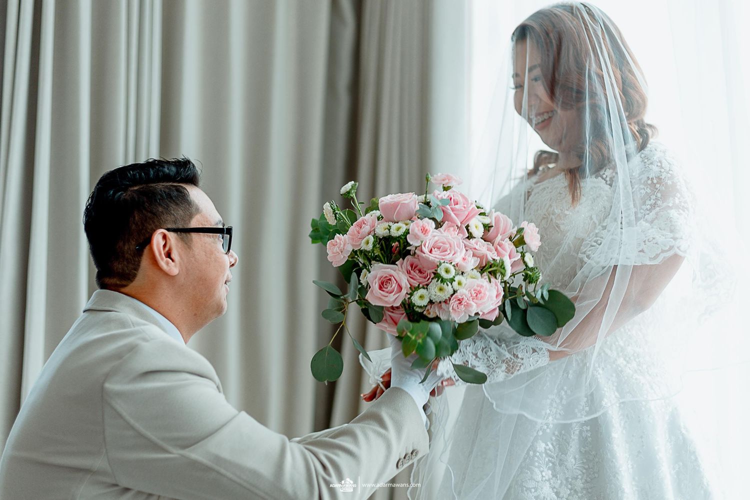 Light-filled wedding moment with pink rose bouquet and delicate lace veil.