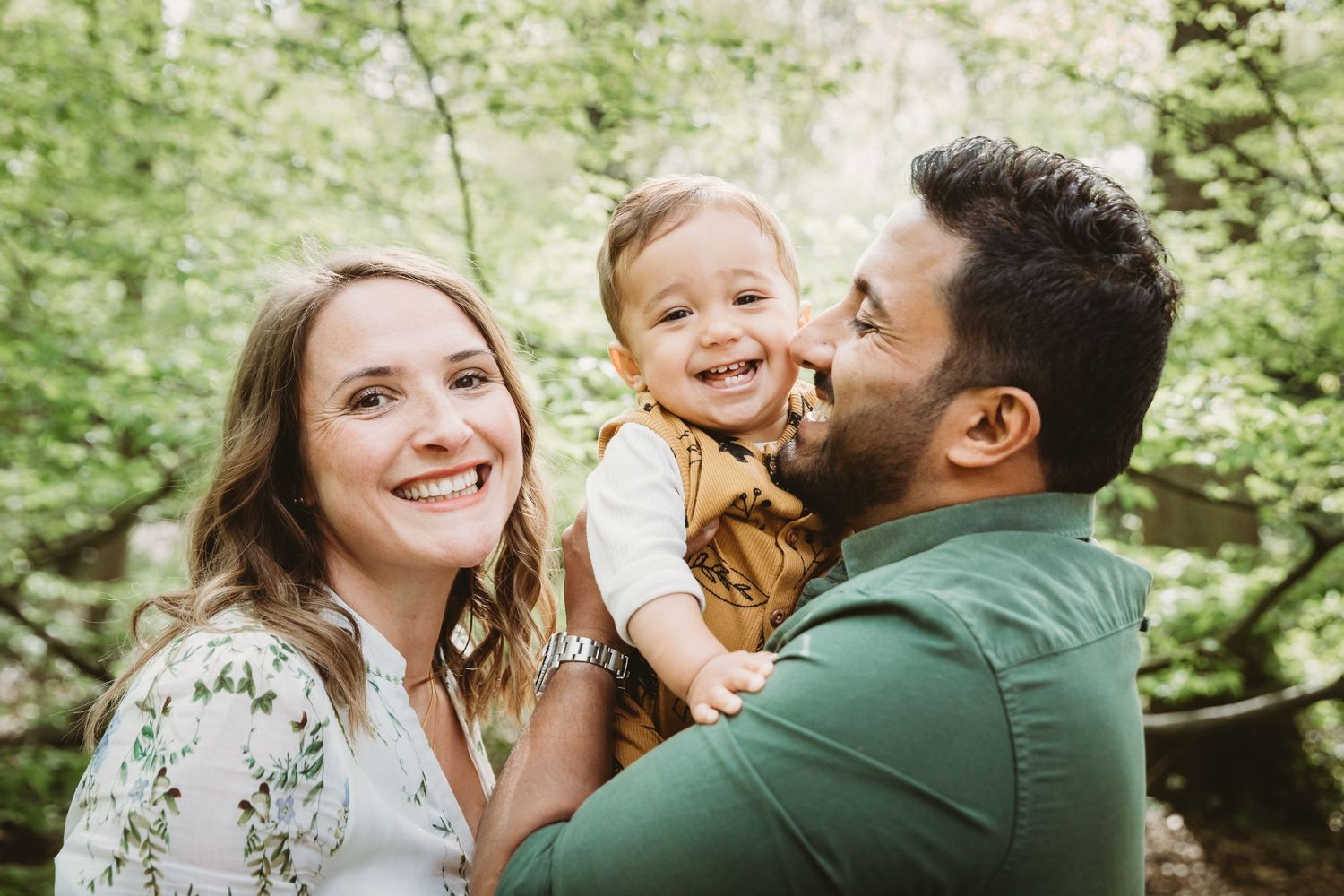 Joyful outdoor family portrait captured in a lush green forest setting.