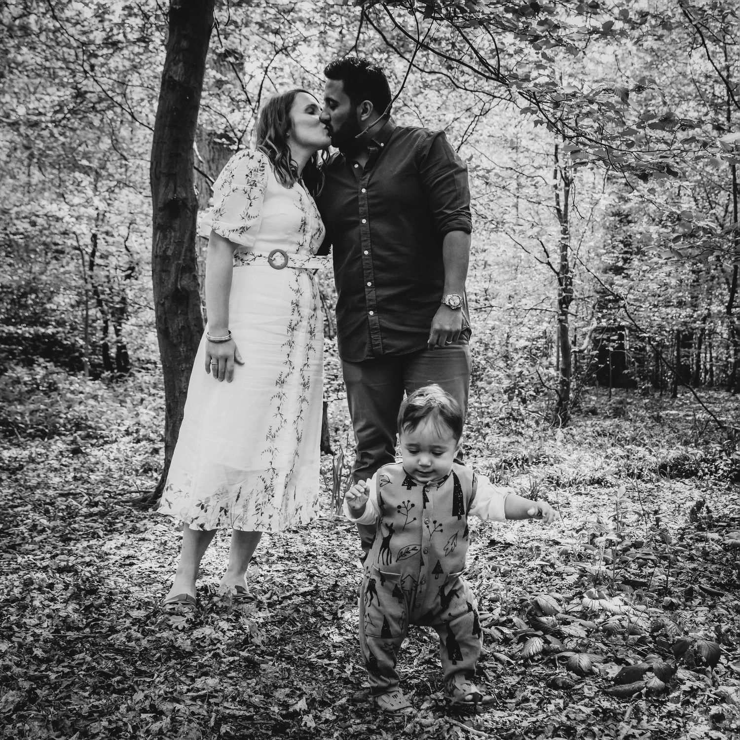 A black and white photo of a relaxed family moment in a wooded forest setting, Highgate Woods, London.